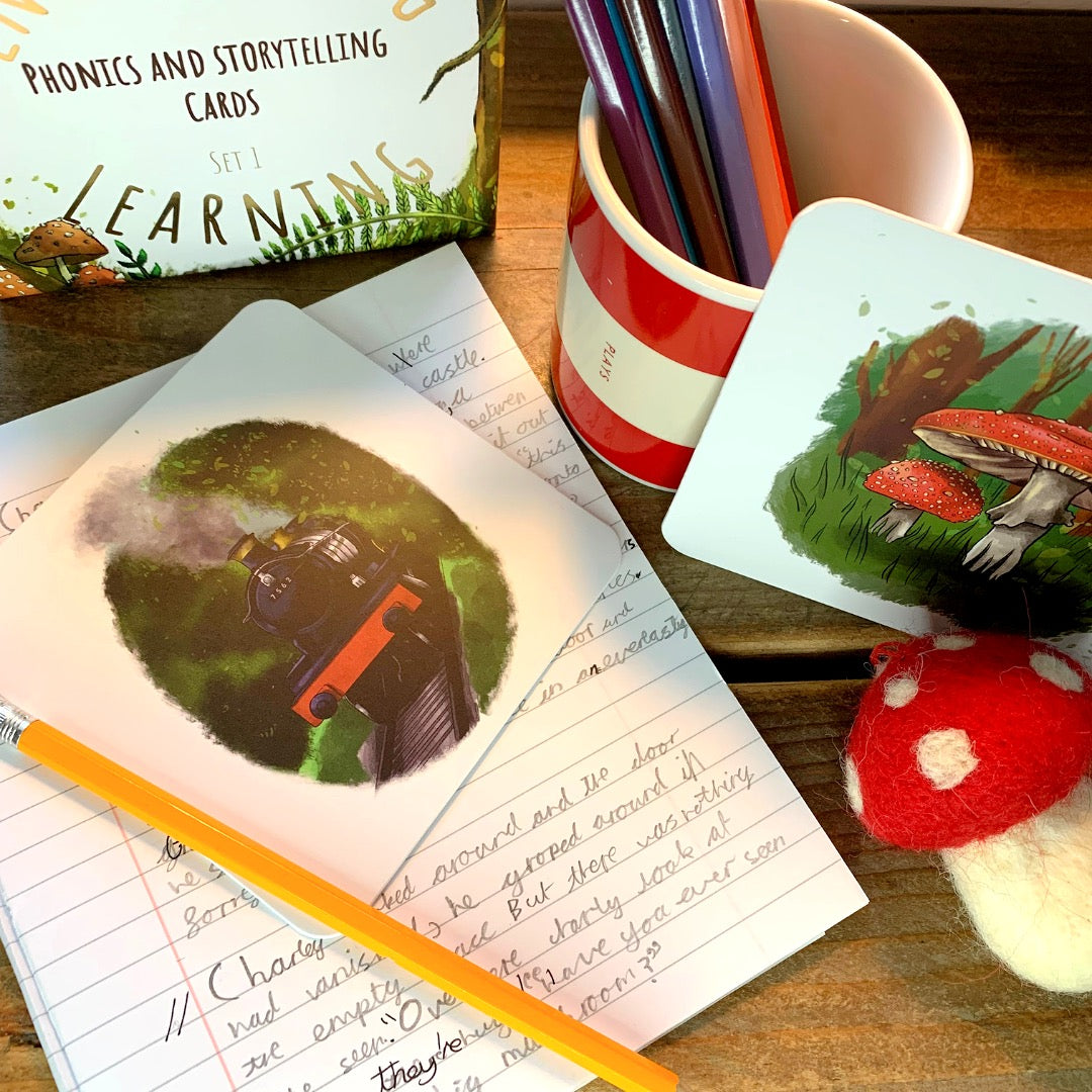 Train storytelling card and mushroom card with pot of pencils and writing book.