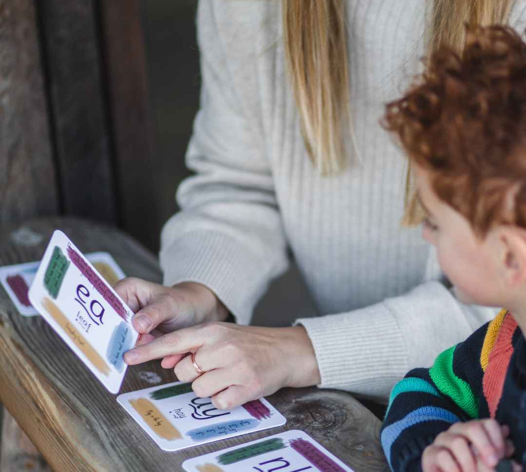 Mother and child using phonics cards at a table.