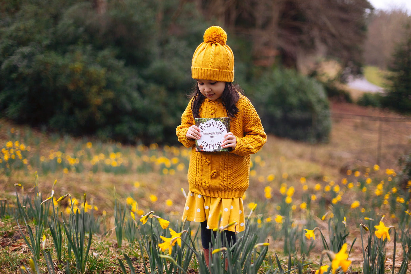 Girl walking with her storytelling cards while in flower field.