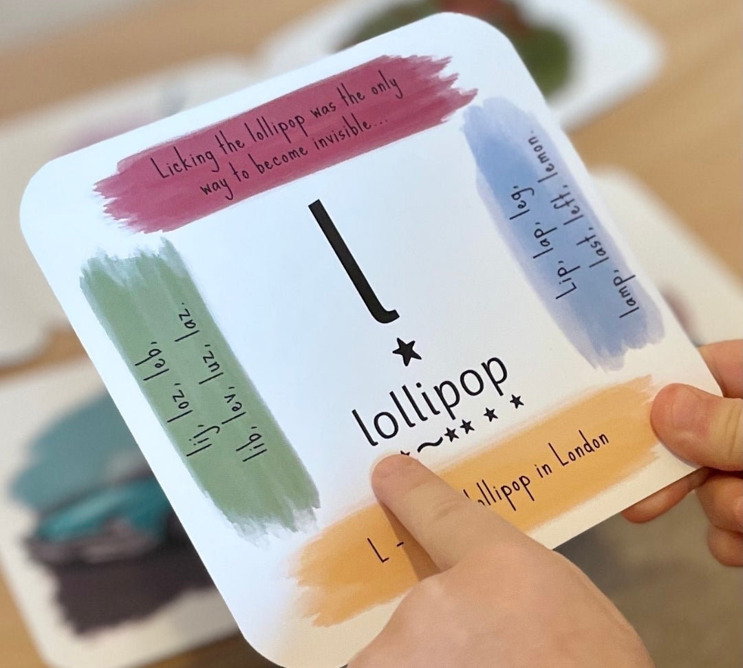 Child's hand holding phonics card showing the 'l' sound.