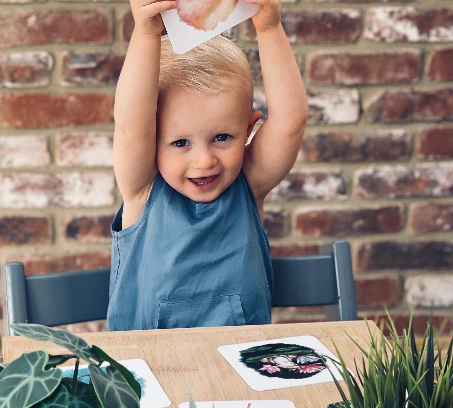 Boy sat at table holding up his rainbow phonics card.