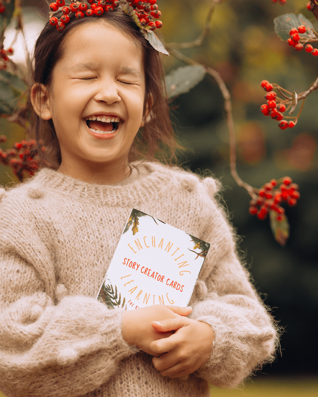 Laughing child with eyes shut holding story creator cards for creative writing.