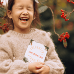Laughing child with eyes shut holding story creator cards for creative writing.
