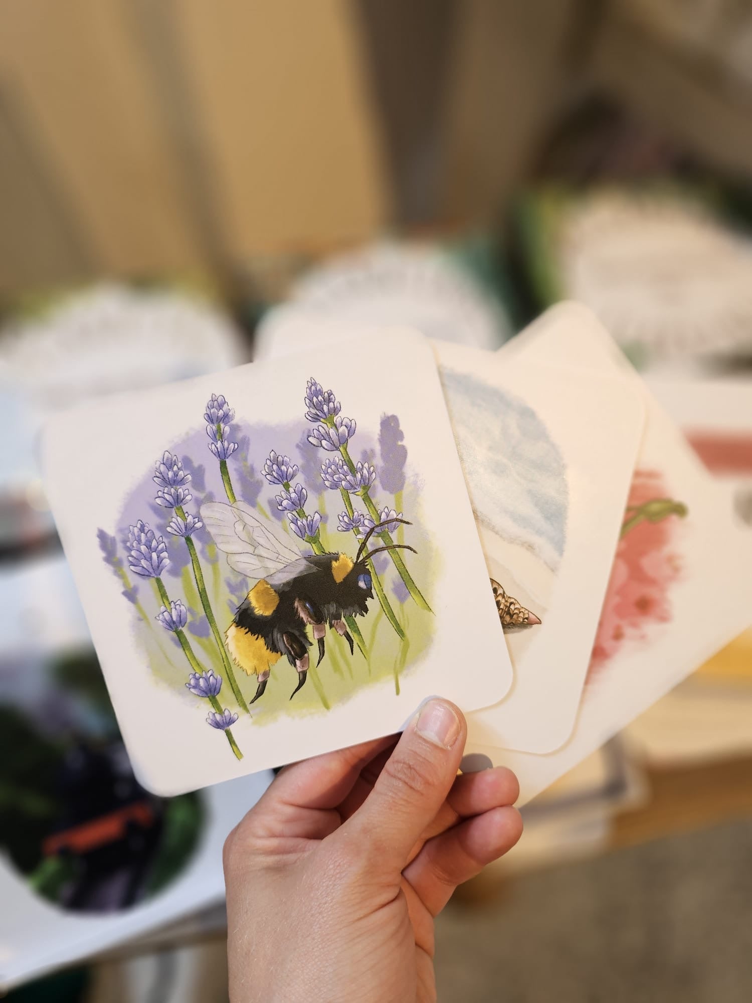 A hand holding a card showing a bumble bee illustration.