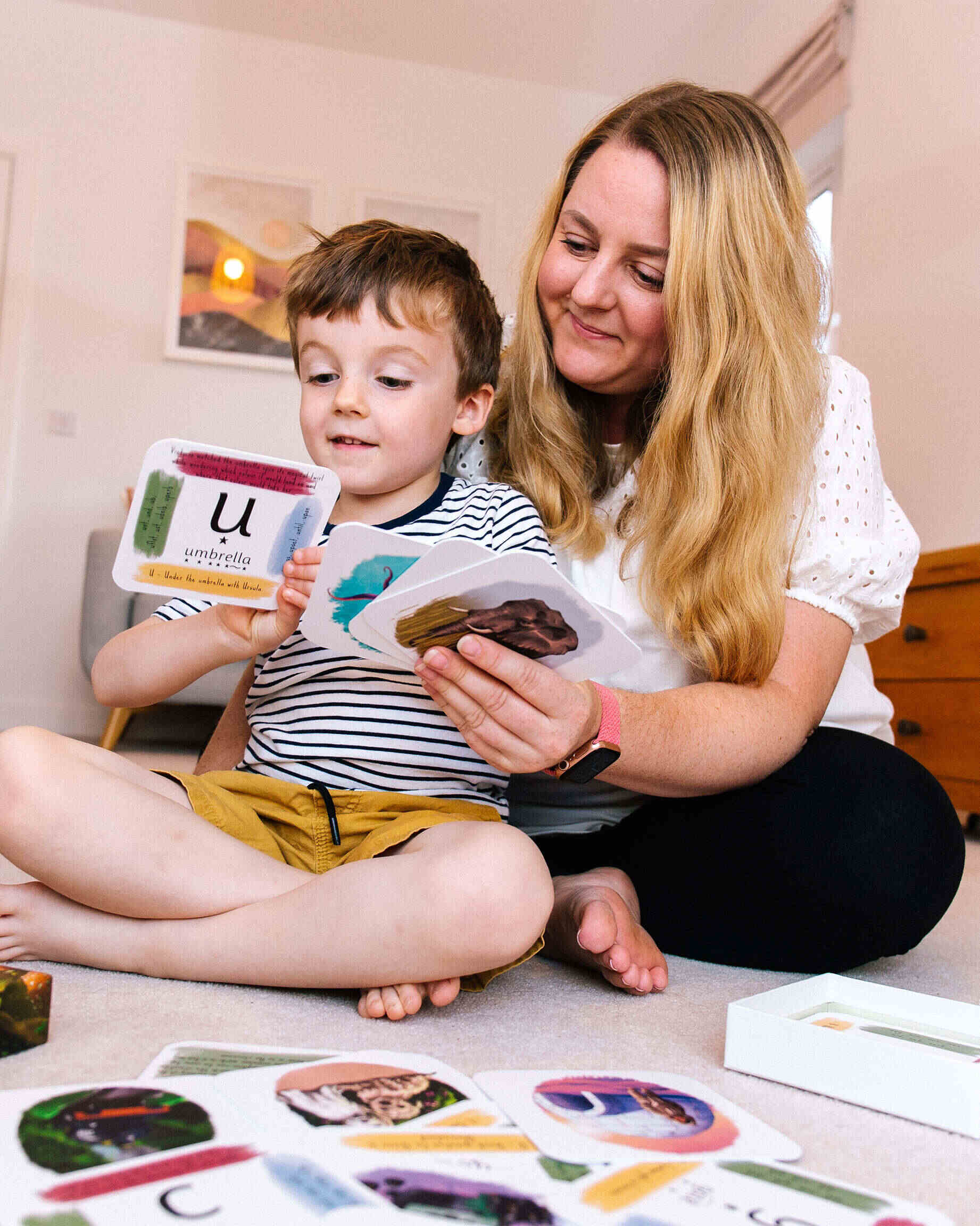 Young boy with his mum looking at phonics cards showing sounds and pictures.