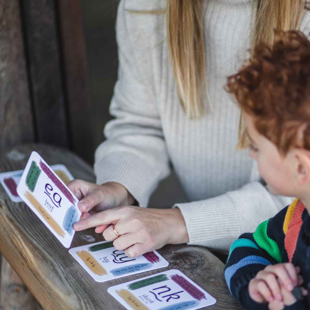 Mother and child using phonics cards at a table.