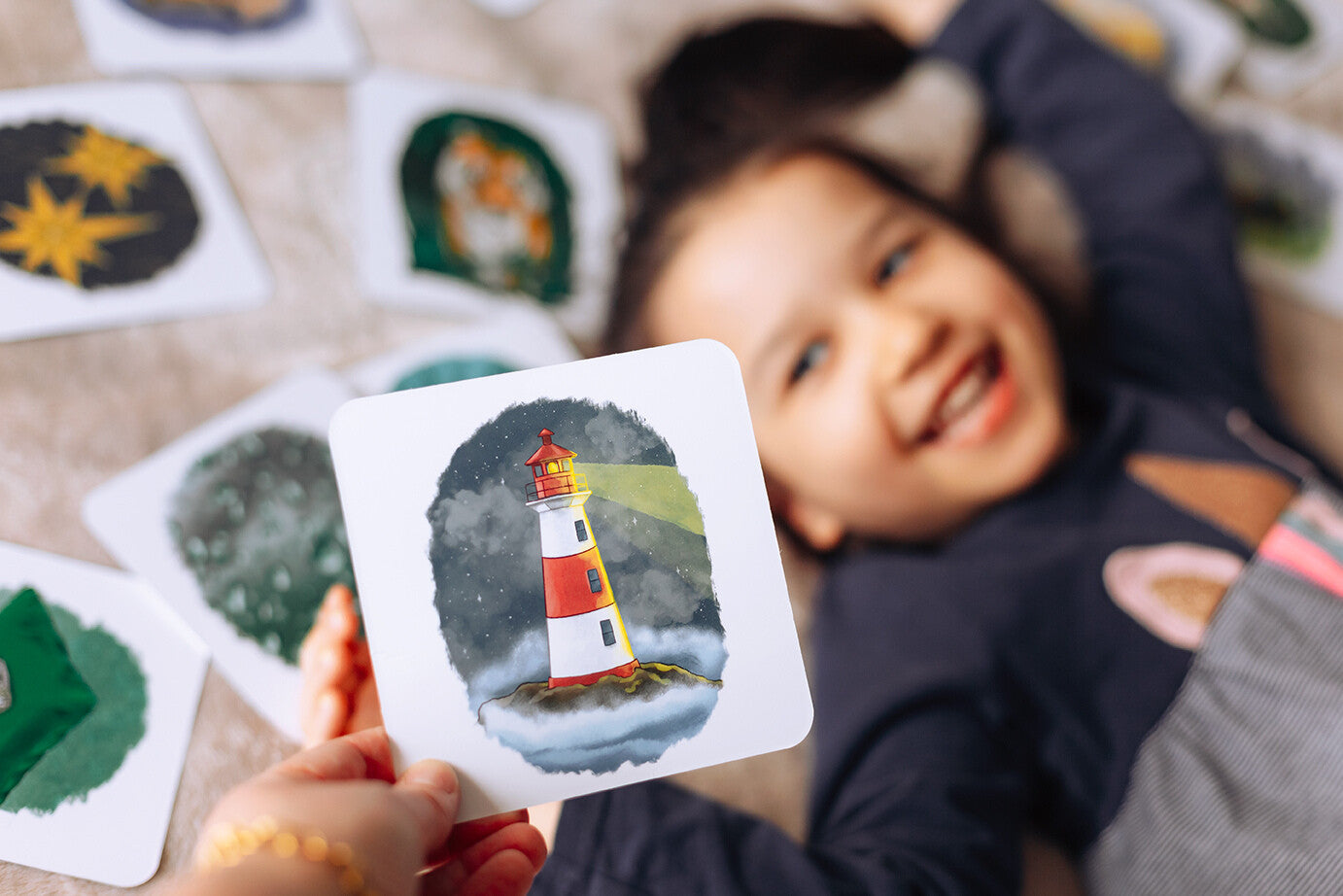 Smiling girl holding up a lighthouse card.