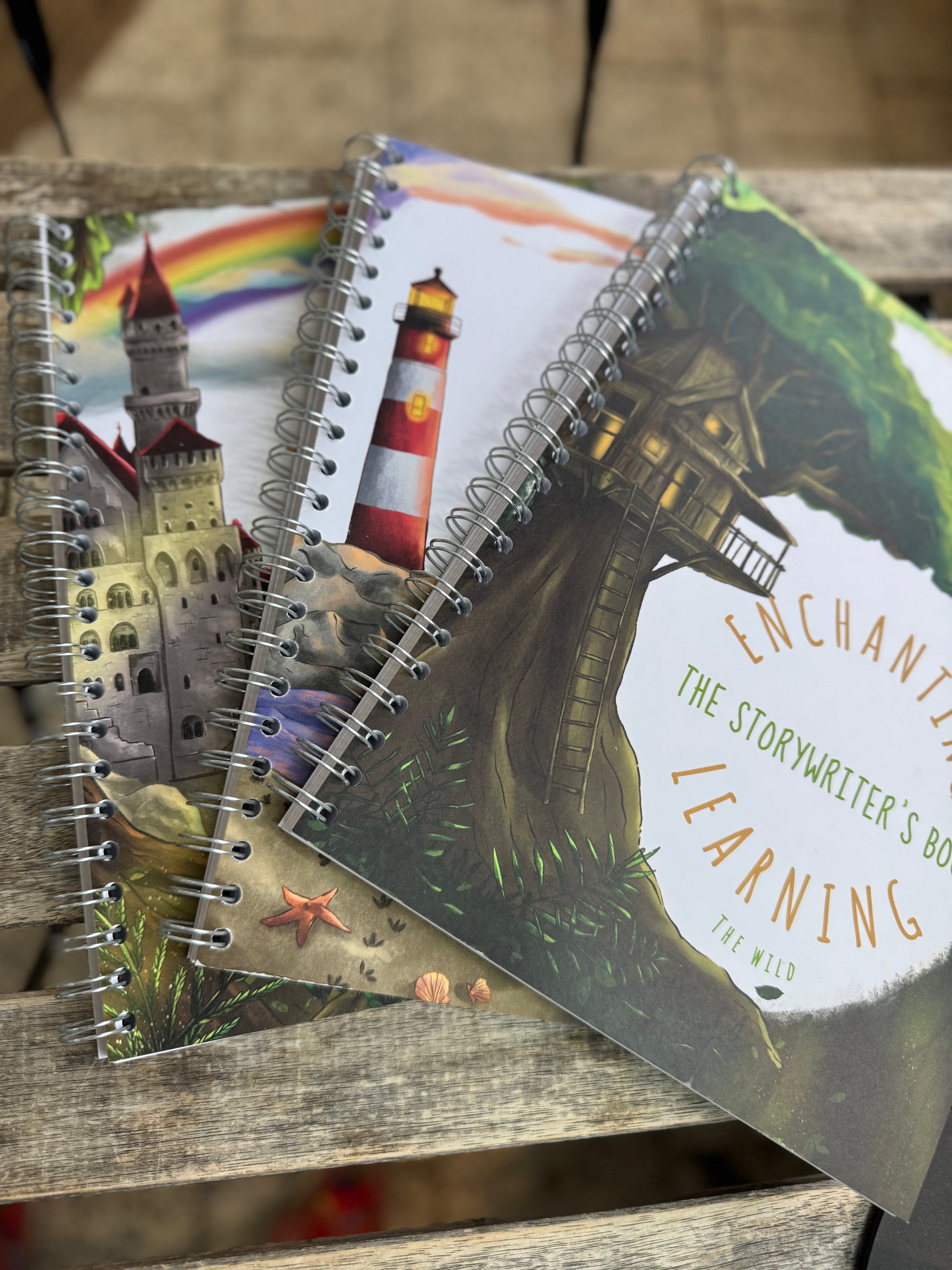 Three writing books displayed on a table. One showing a jungle scene , one showing a lighthouse and one showing a castle.