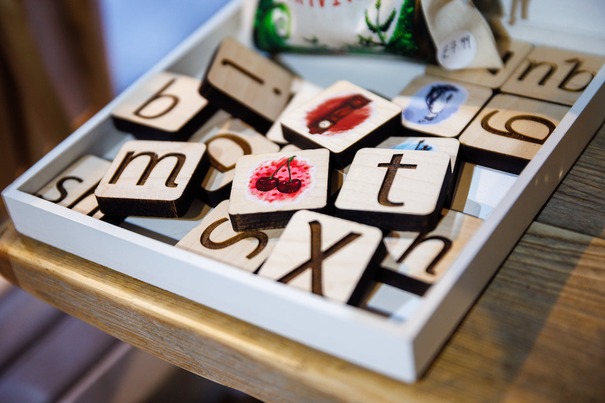 A tray of phonic tiles showing letters and linking pictures.