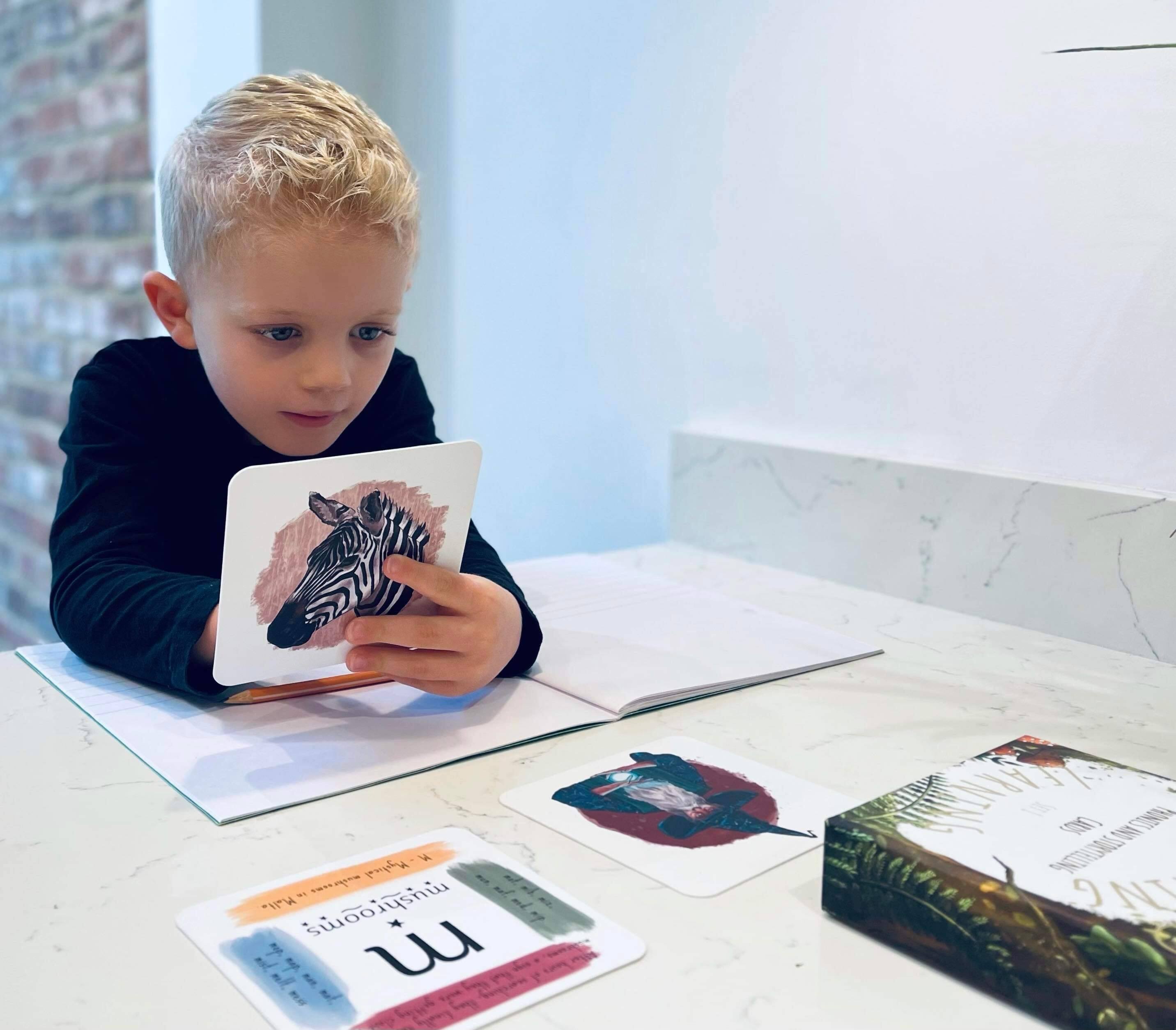 Boy using storytelling and phonics cards for writing.