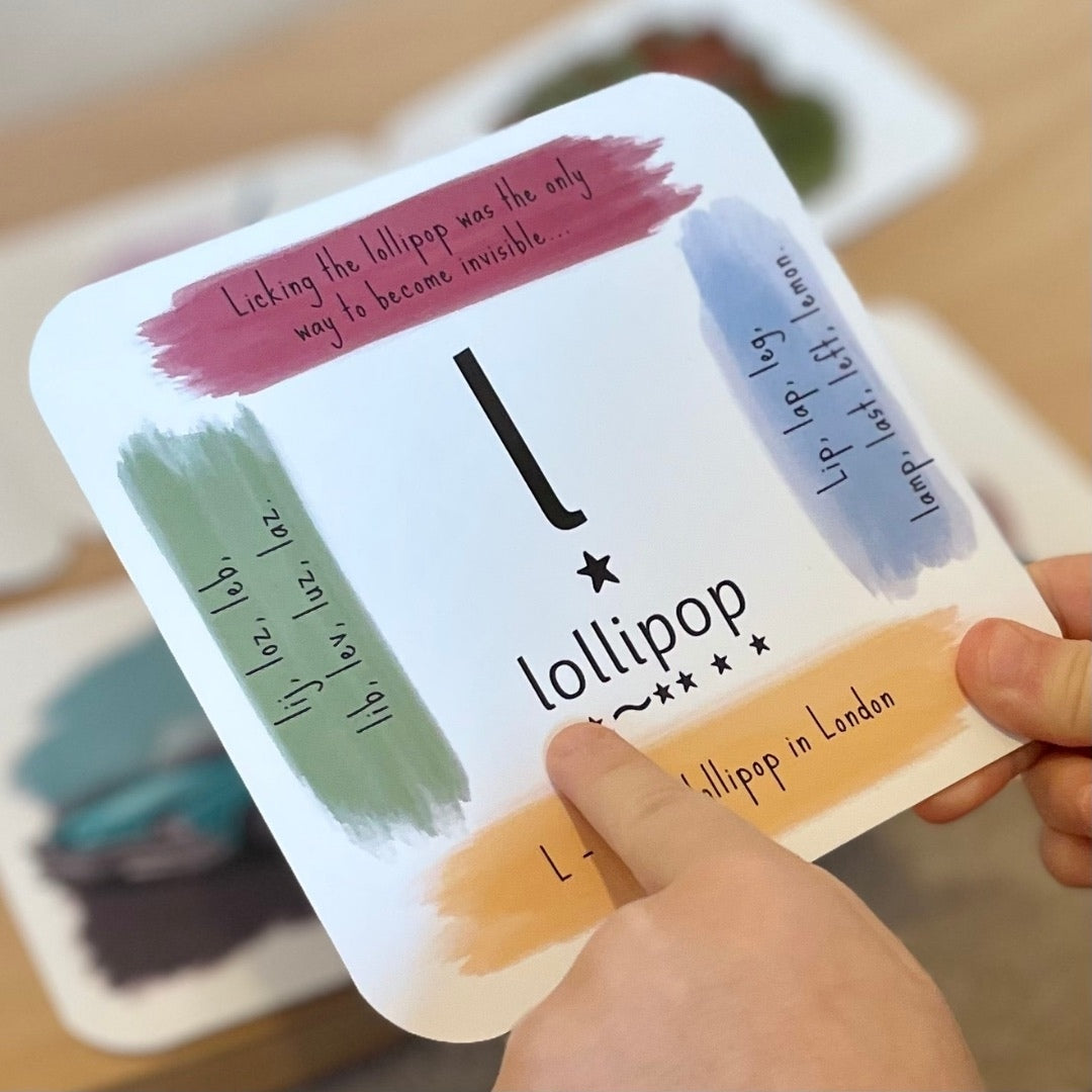 Child's hand holding phonics card showing the 'l' sound.