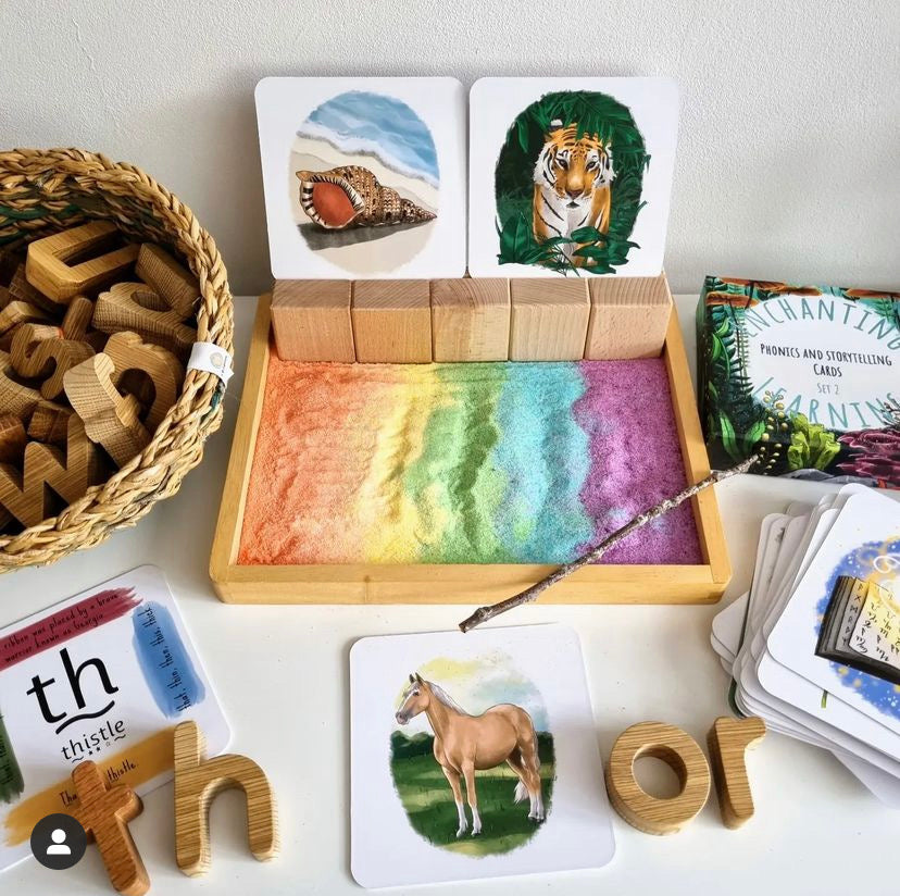 Colourful sand tray set up for writing with phonics cards showing tiger, shell and horse.