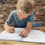 Young boy writing in his story writing book.