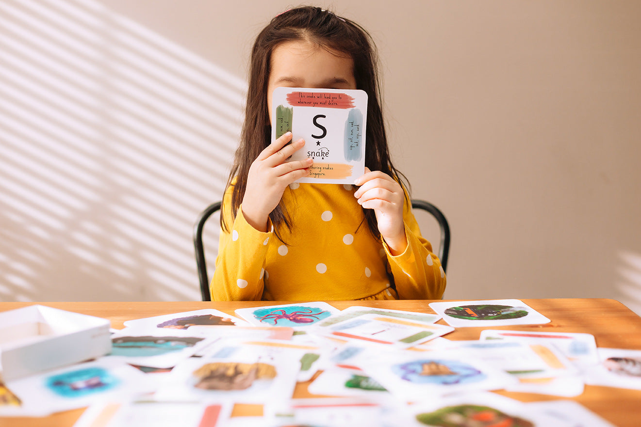Child using phonics cards at a table.