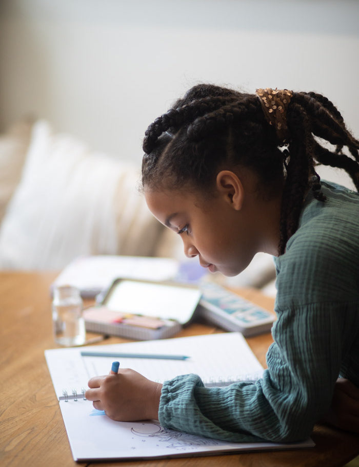 A young girl illustating in her storywriter's book.