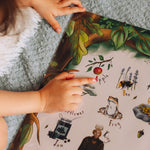 A child's hand pointing to a capital a on a woodland themed poster.