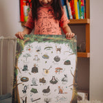 A child holding her woodland alphabet poster, smiling.