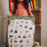 A child holding her woodland alphabet poster, smiling.