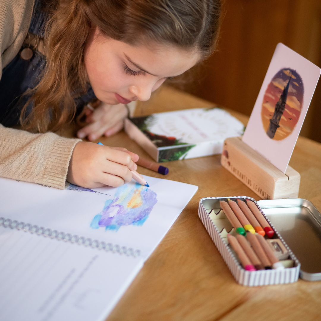 girl using book and pencils at wooden table.