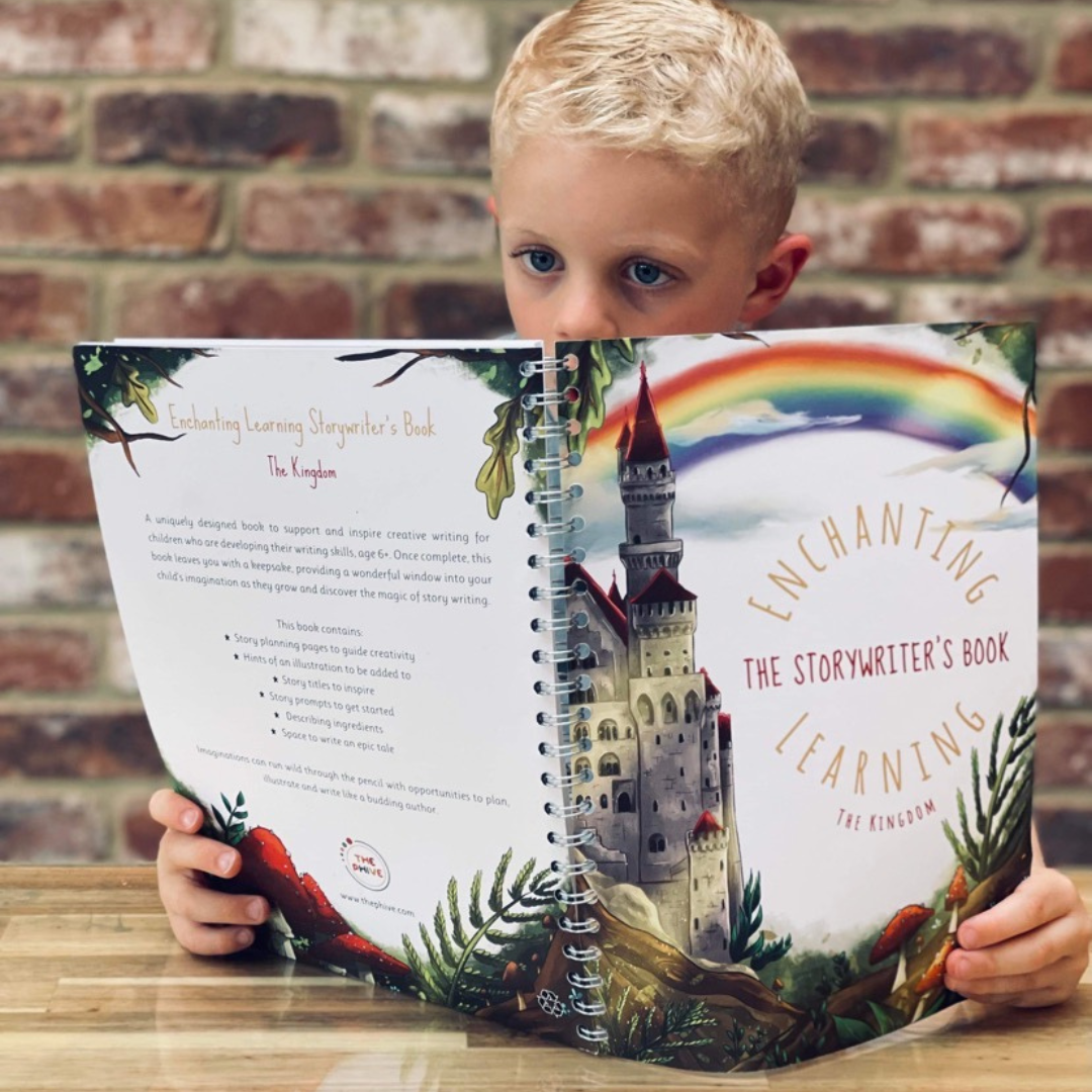 a boy sat at a table reading his writing book.