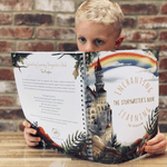 Young boy reading a story in his story writing book.