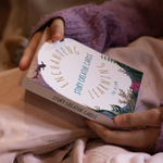 Person holding a book titled 'Enchanting Learning Story Creator Cards' with a soft focus background.