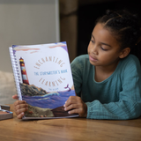 Young girl reading a book titled 'Enchanting Learning' with a lighthouse illustration on the cover.