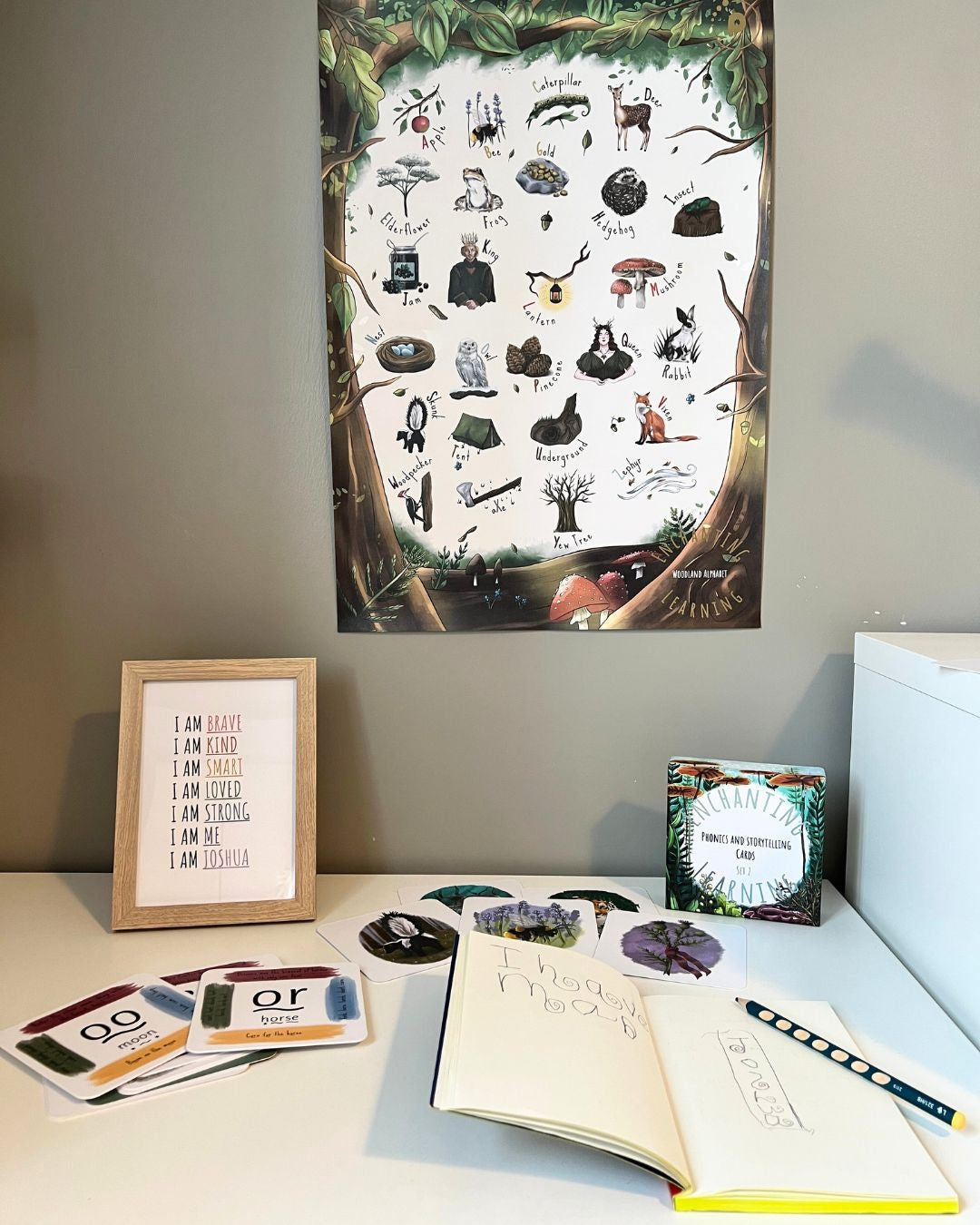 The woodland alphabet poster hanging above a desk with enchanting learning cards below.