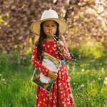 Girl blowing a dandelion in meadow while holding her story writing book.