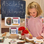 Girl with pencil playing schools with her phonics cards.