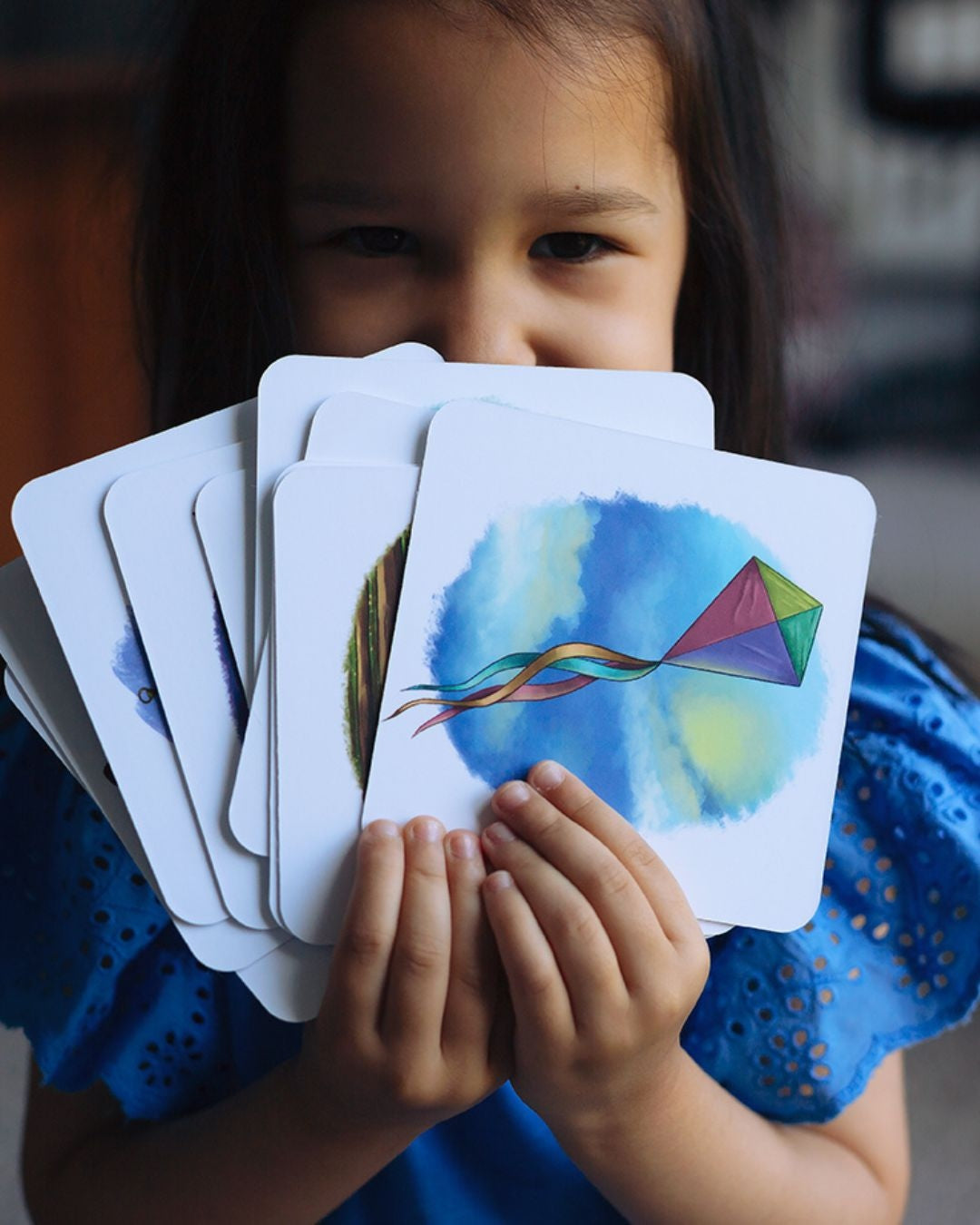 Smiling girl holding fanned out Set 3 phonics cards.