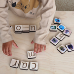 girl playing with wooden tiles to build words.