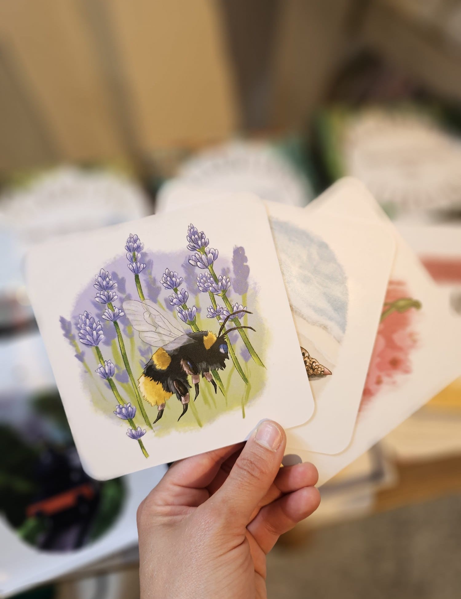 A hand holding a card showing a bumble bee illustration.