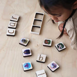 Child looking at maple wood phonics tiles.