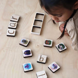 Child looking at maple wood phonics tiles.