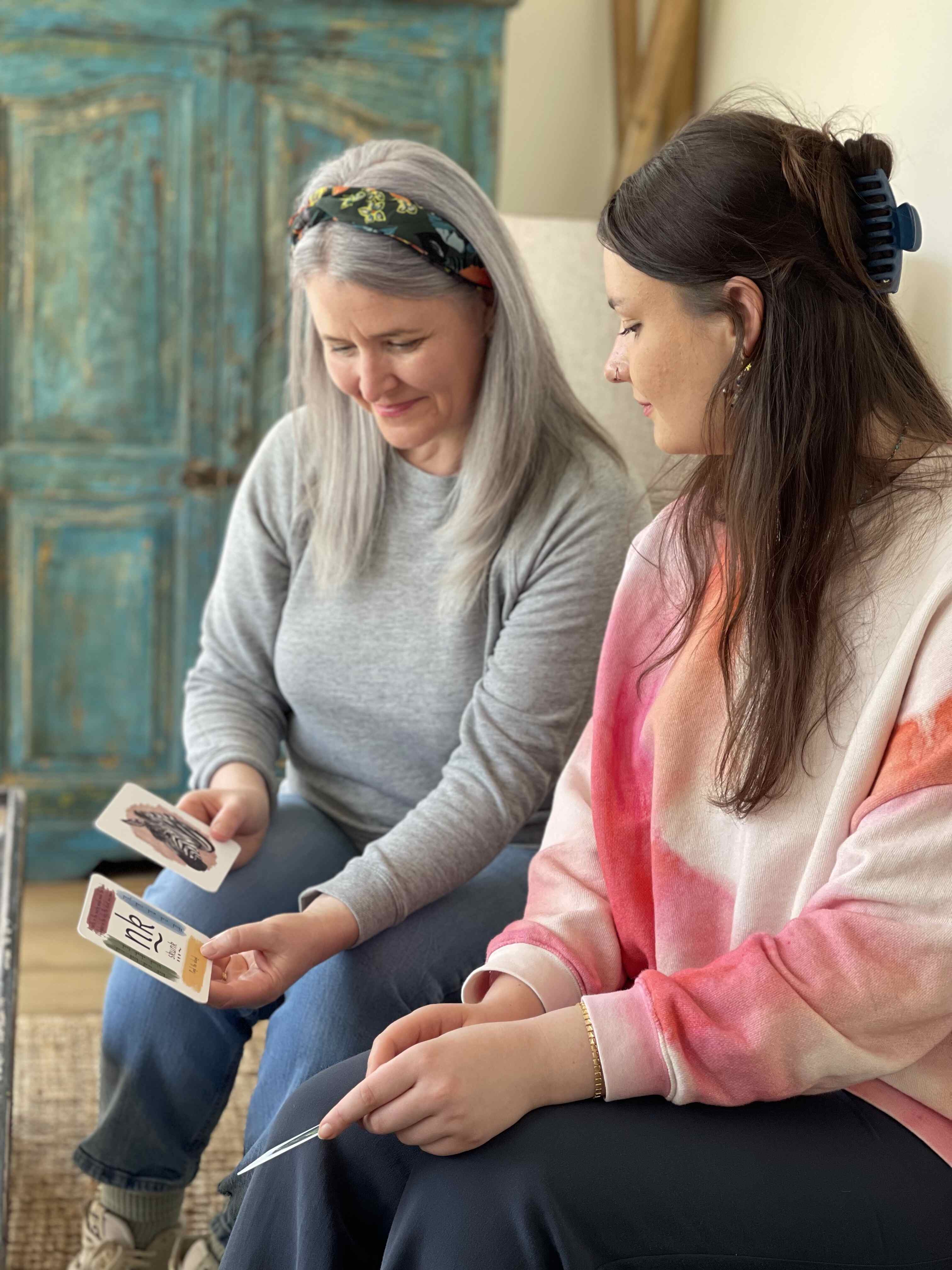 Mother and daughter sat looking at phonics cards they designed.