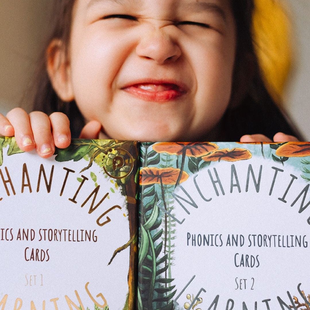 Smiling girl holding two sets of phonics and storytelling cards.