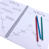 An open story writing book showing the planning pages with pencils laying on the page.