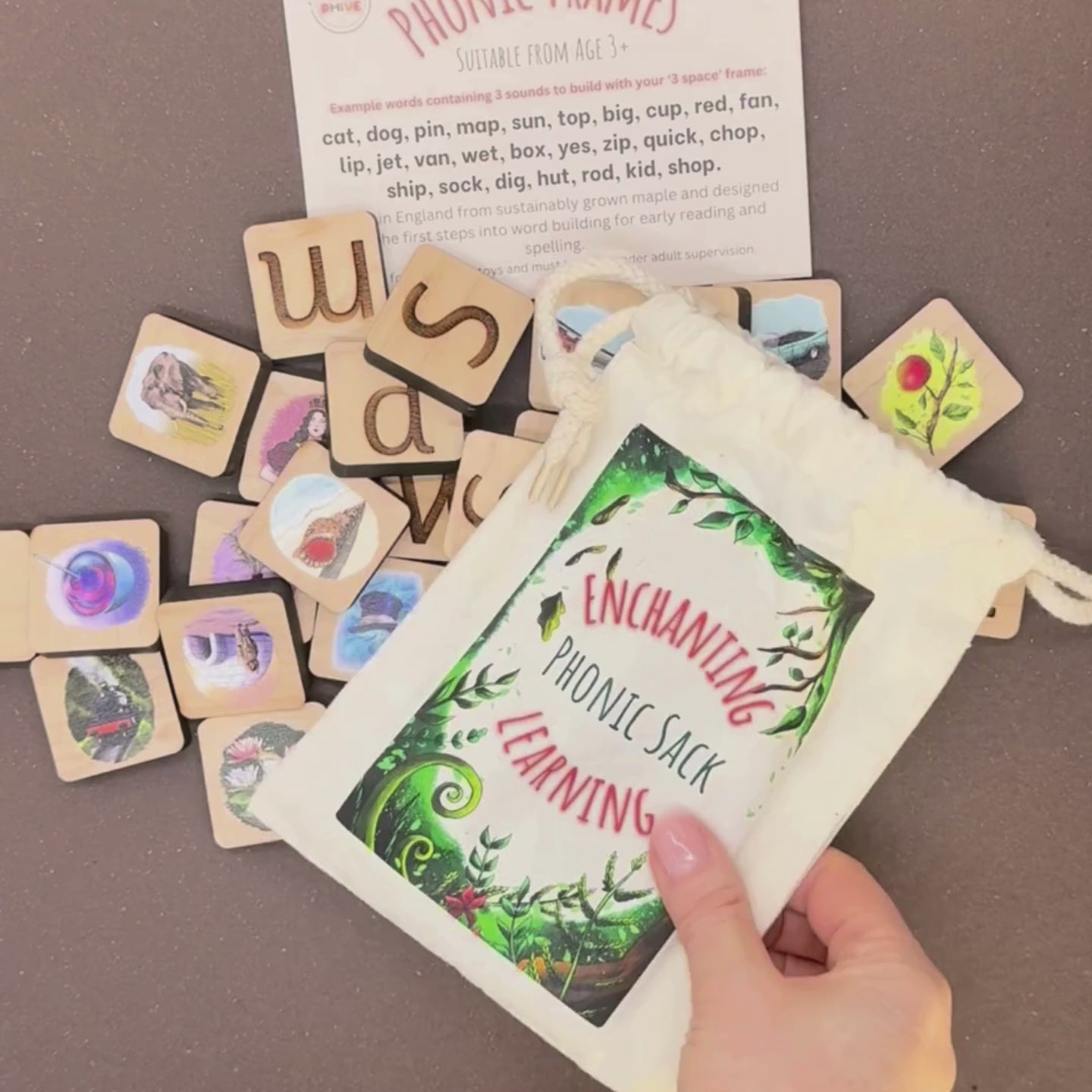phonic tiles with letters and pictures, a cotton sack for phonics games, a word suggestion card and wooden word building frames.