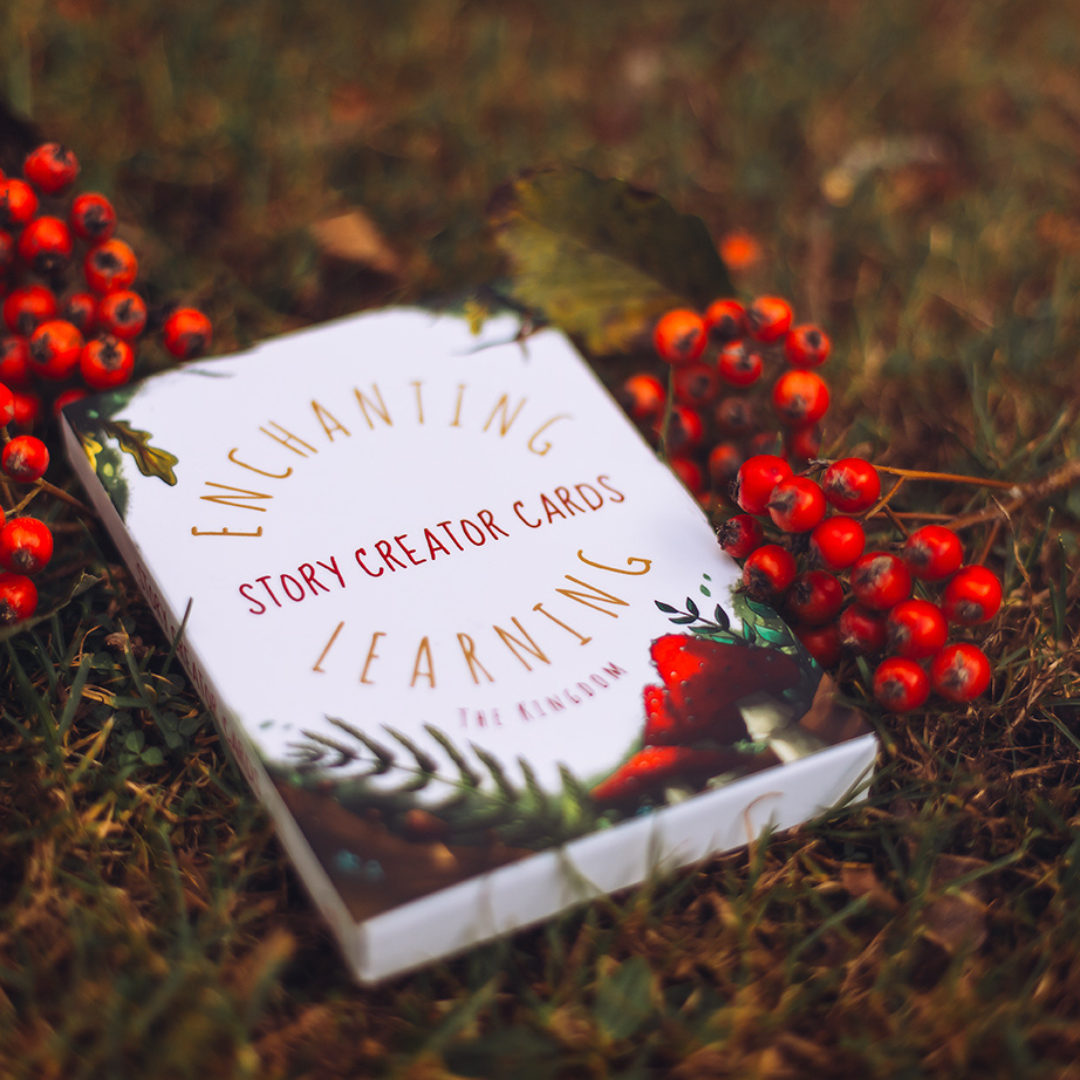 a pack of story creator cards in the grass with berries.