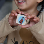 child smiling showing a close up of the violin phonic tile for reading.