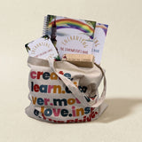 Tote bag with motivational phrases, books, and cards on a beige background