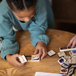 girl in blue dress building words using wooden phonic tiles.