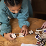 girl in blue dress building words using wooden phonic tiles.