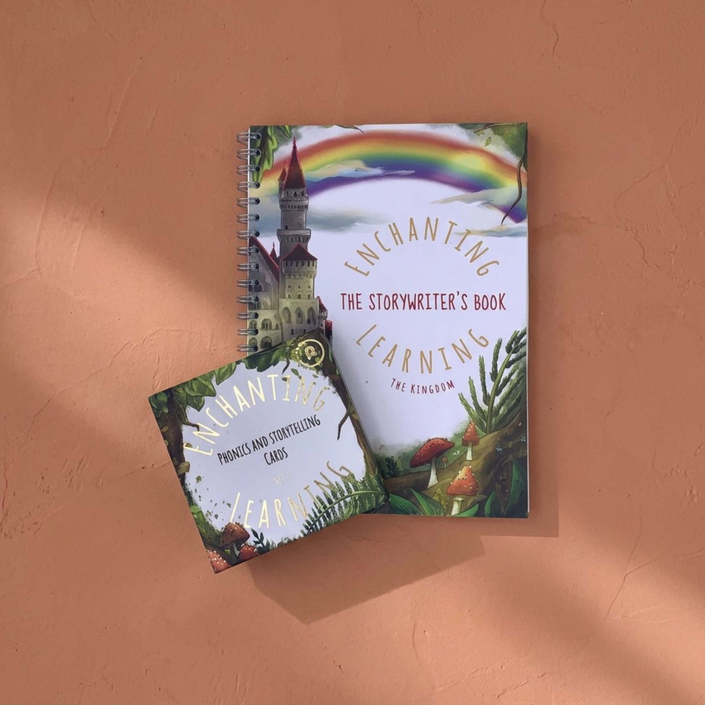  A book titled 'Enchanting Learning' on a textured orange surface with phonic cards.