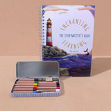 kids writing book with lighthouse illustration and set of colored pencils in a tin on a beige background