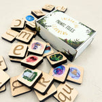 Wooden phonetic tiles with colorful designs and a box labeled 'Phonic Tiles' on a light background.