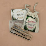 a white box with ferns containing wooden phonic tiles with two word building wooden frames, a suggestion card and a cream, cotton play sack.