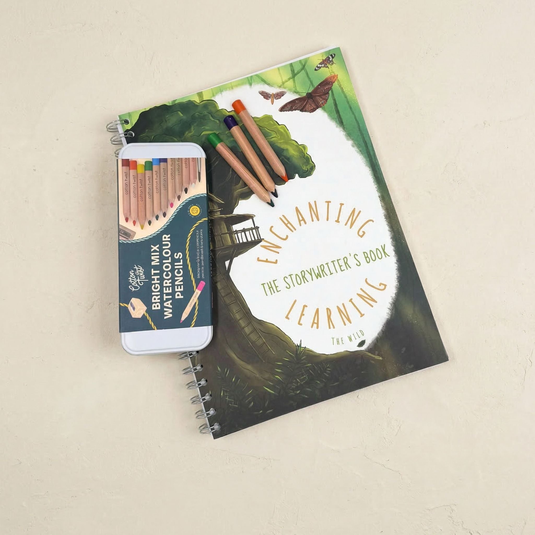 writing book with nature-themed cover and watercolor pencils on a beige background