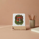 Phonics card with mushroom illustration on a stand, next to a cup of pencils on a beige background